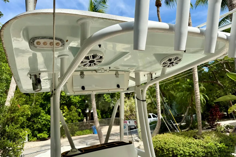 Slide: The Image of 2015 Sea Hunt Ultra 234 boat T-top with speakers and rod holders, surrounded by tropical greenery. - 9