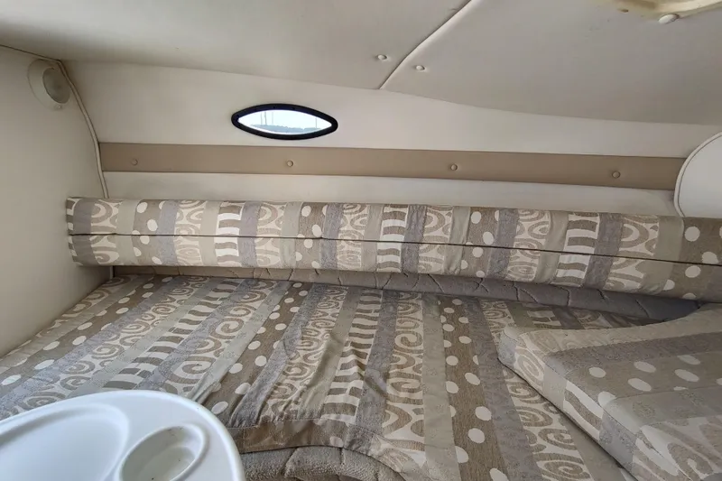 Slide: The Image of 2005 Rinker 232 Captiva Cuddy cabin interior with patterned upholstery and small window. - 23