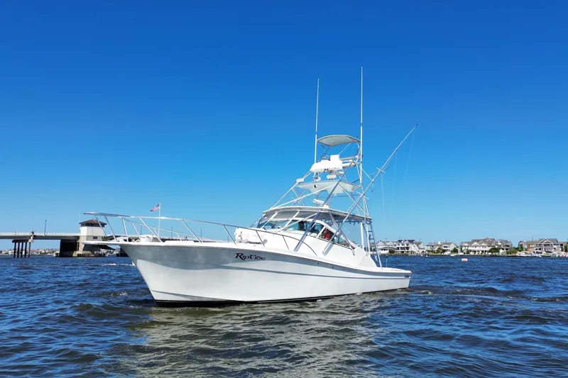 Slide: The Image of 2006 Topaz 40 Express boat on water, clear blue sky, bridge and houses in background. - 14