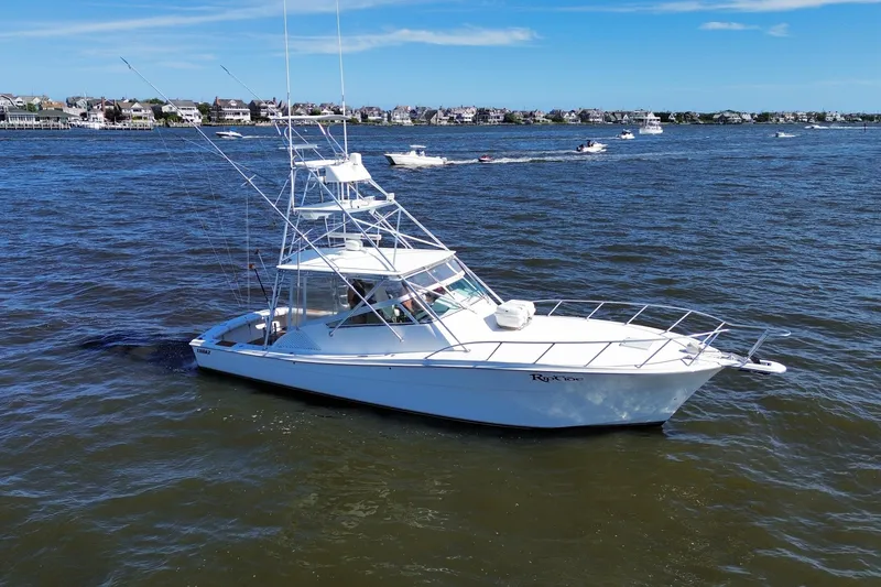Slide: The Image of 2006 Topaz 40 Express boat on water, with coastal houses in the background. - 16