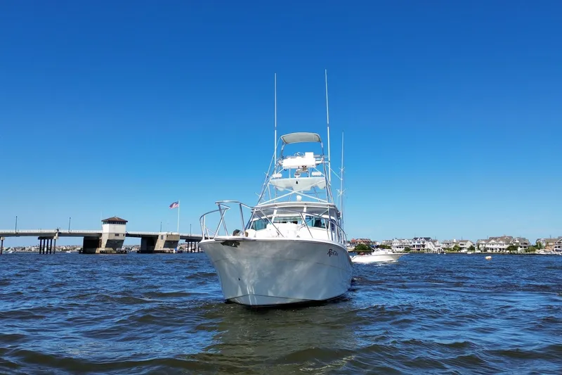 Slide: The Image of 2006 Topaz 40 Express boat on water near bridge and coastal homes under clear blue sky. - 2