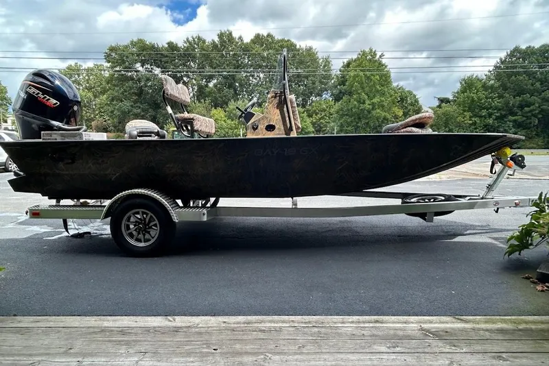 Slide: The Image of 2025 G3 Bay 19 GX Tunnel boat on trailer, parked outdoors with trees in background. - 1