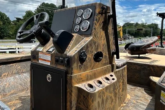 Slide: The Image of 2025 G3 Bay 19 GX Tunnel boat console with camo design and steering wheel. - 2