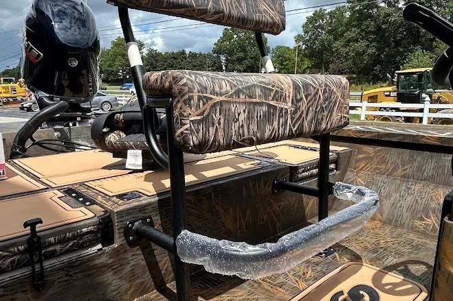 Slide: The Image of 2025 G3 Bay 19 GX Tunnel boat with camo seating and motor, parked outdoors. - 7