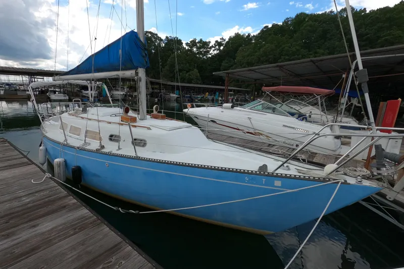 The Image of 1976 Ranger 33 sailboat docked at marina, featuring blue hull and white deck. - 0