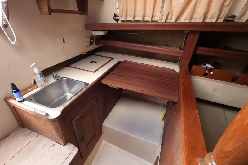Slide: The Image of 1976 Ranger 33 boat interior with compact kitchen, sink, and wooden cabinetry. - 13