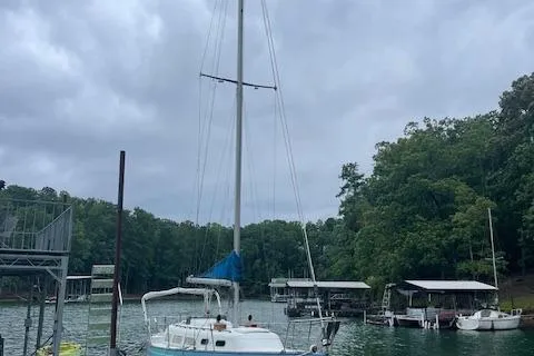 Slide: The Image of 1976 Ranger 33 sailboat docked on a serene lake with lush green trees. - 5