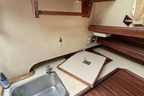 Slide: The Image of 1976 Ranger 33 boat interior with sink, wooden surfaces, and storage compartments. - 14