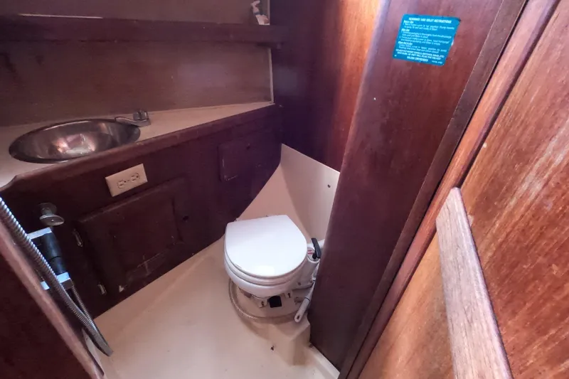 Slide: The Image of 1976 Ranger 33 boat bathroom with wooden interior, sink, and toilet. - 22