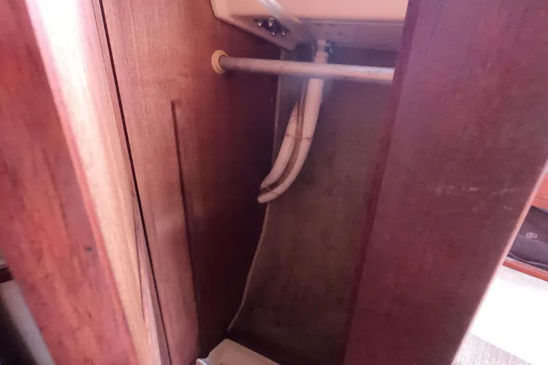 Slide: The Image of Interior view of a 1976 Ranger 33 sailboat showing wooden cabinetry and plumbing pipes. - 25