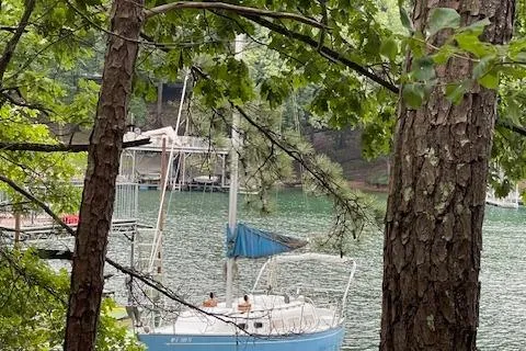 Slide: The Image of Vintage 1976 Ranger 33 sailboat docked on a serene lake, surrounded by lush trees. - 4