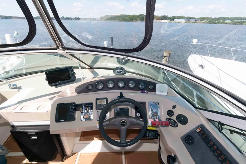 Slide: The Image of 2005 Carver 360 Mariner helm with steering wheel, controls, and navigation equipment on a sunny day. - 12