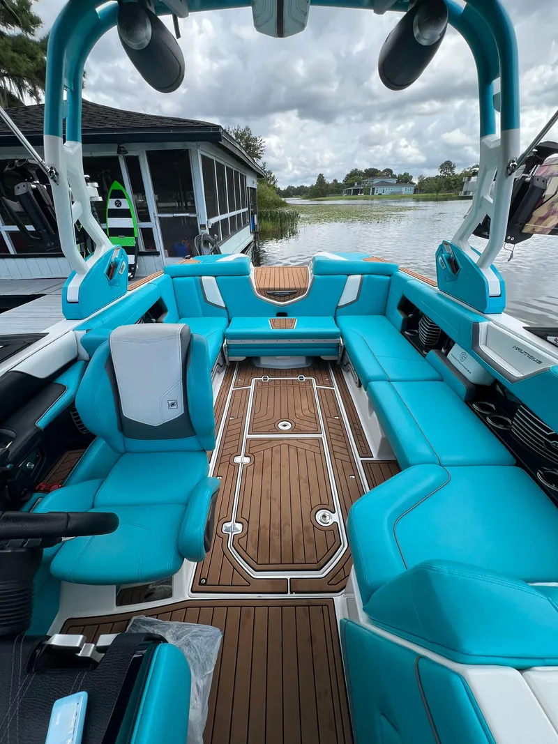 Slide: The Image of 2018 Nautique Super Air G23 boat with turquoise seating and wooden deck, docked by a lake. - 10