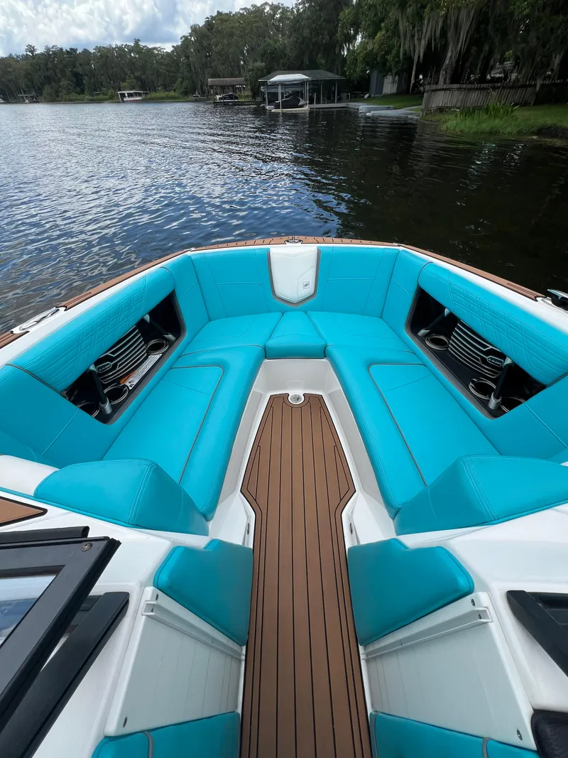 Slide: The Image of 2018 Nautique Super Air G23 boat with turquoise seating on a calm lake. - 2