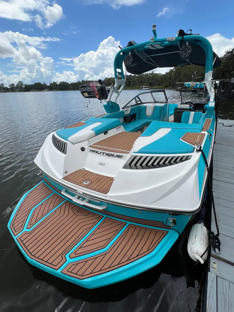 Slide: The Image of 2018 Nautique Super Air G23 boat docked on a lake under a partly cloudy sky. - 8