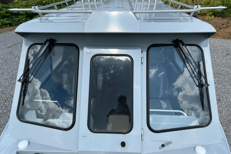 Slide: The Image of 2021 Hewescraft 220 Ocean Pro ET boat windshield with wipers, reflecting cloudy sky. - 26