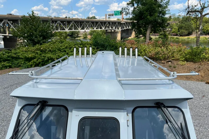 Slide: The Image of 2021 Hewescraft 220 Ocean Pro ET boat with rod holders, near a bridge and greenery. - 27