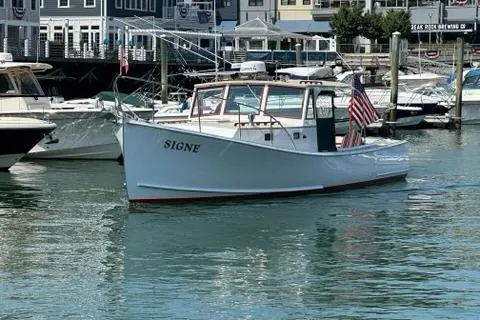 Slide: The Image of 1987 Holland 32 boat named "SIGNE" docked in a marina with waterfront buildings. - 1