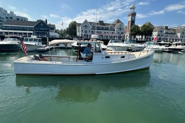 Slide: The Image of 1987 Holland 32 boat docked in a marina with waterfront buildings in the background. - 3