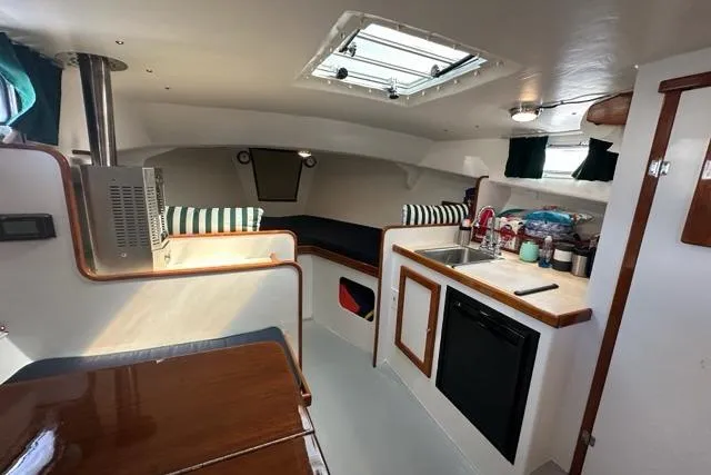 Slide: The Image of Interior of a 1987 Holland 32 sailboat, featuring cozy seating and wooden accents. - 33
