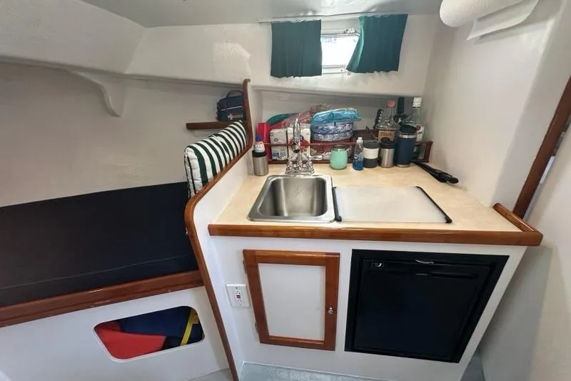 Slide: The Image of Compact kitchen area in a 1987 Holland 32 boat with sink, countertop, and mini fridge. - 39
