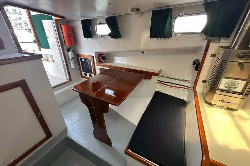 Slide: The Image of Interior of 1987 Holland 32 sailboat with wooden table and seating area. - 42