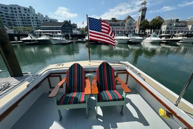 Slide: The Image of 1987 Holland 32 boat with striped chairs, docked in a marina with American flag. - 68