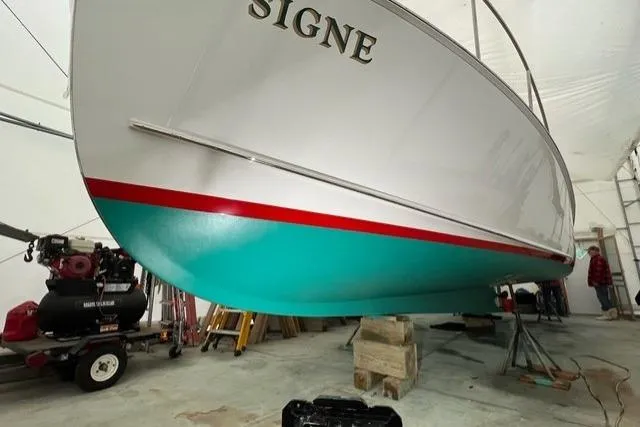 Slide: The Image of 1987 Holland 32 boat named "Signe" in a workshop, featuring a teal and red hull. - 70