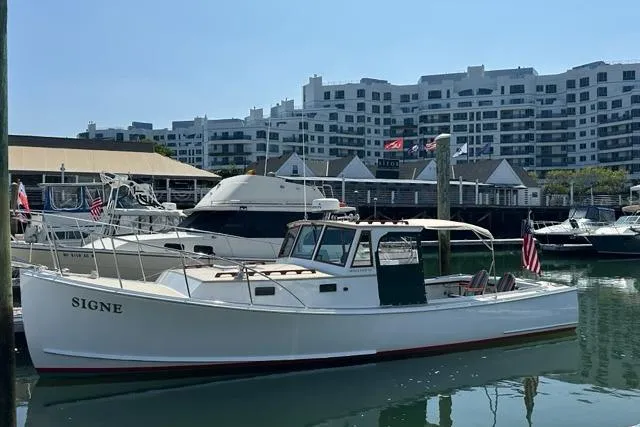 Slide: The Image of 1987 Holland 32 boat docked in marina with modern buildings in background. - 8