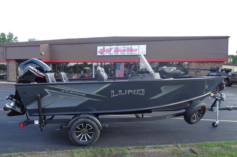 Slide: The Image of 2025 Lund 1675 Adventure SS boat with Mercury engine, parked outside a dealership. - 2