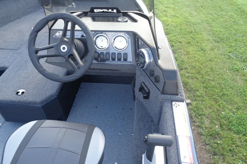 Slide: The Image of 2025 Lund 1675 Adventure SS boat dashboard with steering wheel and controls, on grassy background. - 21