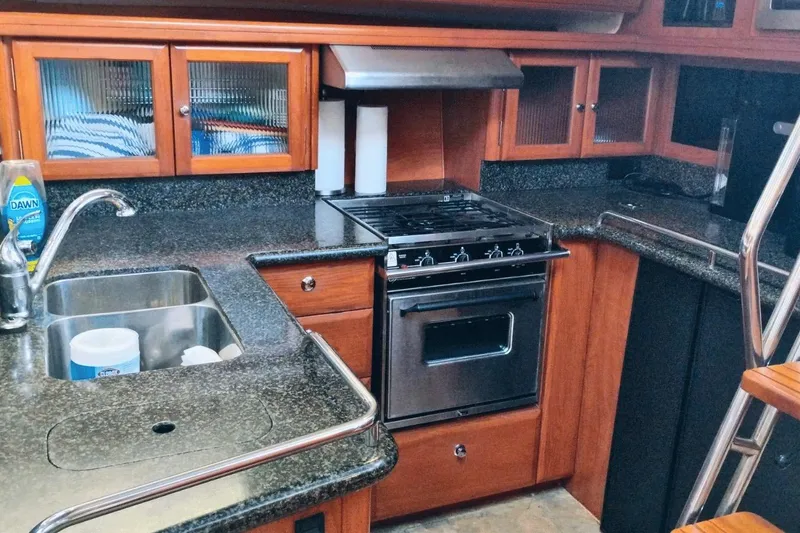 Slide: The Image of 2009 Hunter 50 Center Cockpit kitchen with stove, sink, and wooden cabinets. - 9