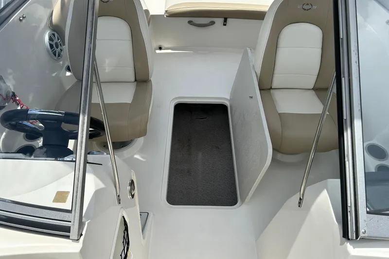 Slide: The Image of 2018 Stingray 191 DC boat interior with beige seats and open storage compartment. - 14