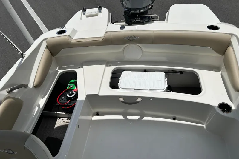 Slide: The Image of 2018 Stingray 191 DC boat interior with seating, storage compartments, and visible battery. - 15