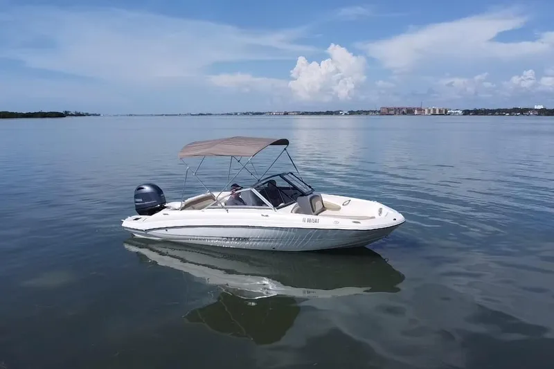 Slide: The Image of 2018 Stingray 191 DC boat on calm water with a canopy under a clear sky. - 17
