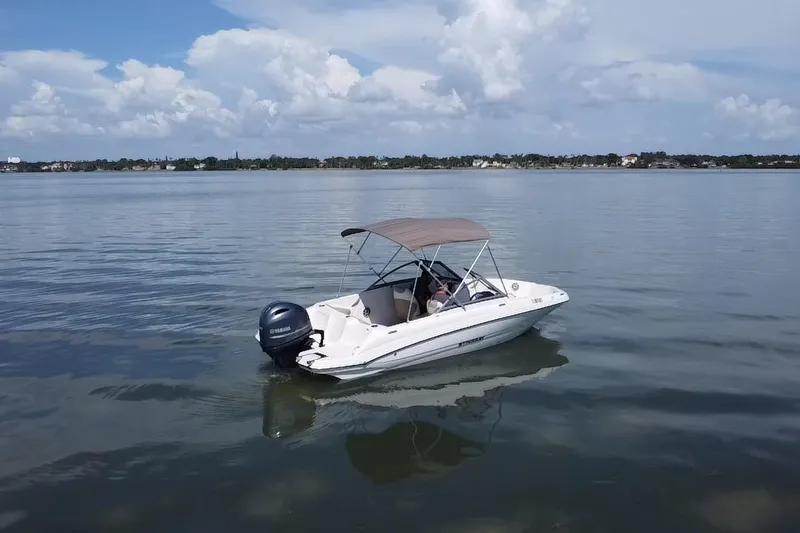 Slide: The Image of 2018 Stingray 191 DC boat on calm water under a cloudy sky. - 18