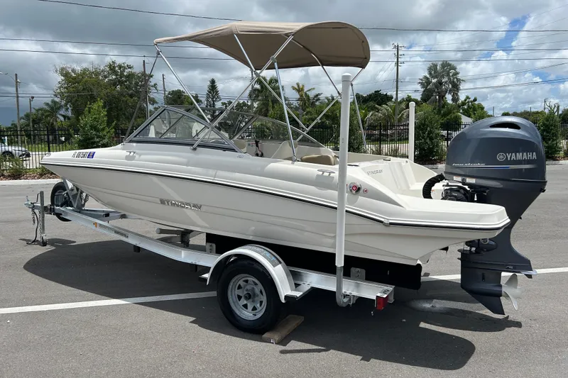 Slide: The Image of 2018 Stingray 191 DC boat on trailer with Yamaha outboard motor, parked outdoors. - 3