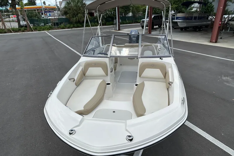 Slide: The Image of 2018 Stingray 191 DC boat with beige seating, parked in a lot. - 5