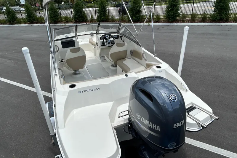 Slide: The Image of 2018 Stingray 191 DC boat with Yamaha 90 engine, parked on asphalt. - 6
