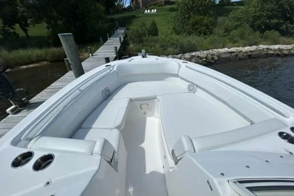 Slide: The Image of 2019 Edgewater 262 CX boat docked by a wooden pier, showcasing spacious seating. - 15