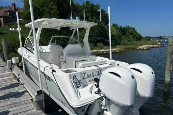 Slide: The Image of 2019 Edgewater 262 CX boat docked, featuring twin outboard engines and sleek design. - 18
