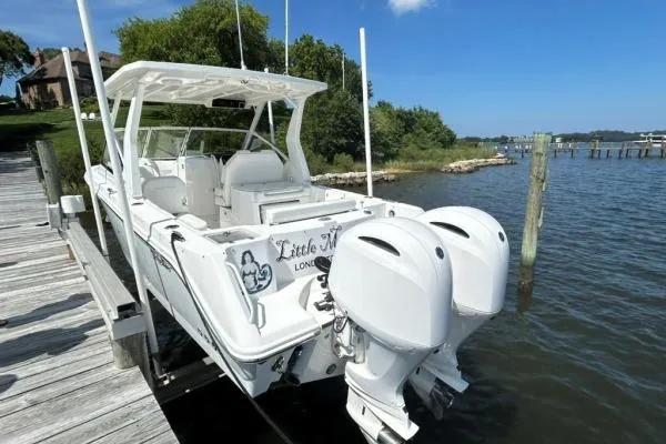 Slide: The Image of 2019 Edgewater 262 CX boat docked by a scenic waterfront with twin engines. - 2