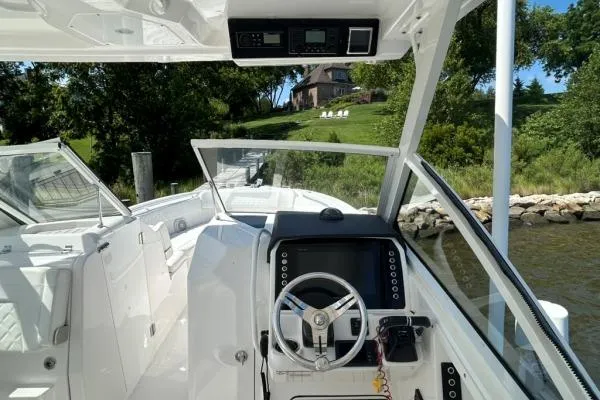 Slide: The Image of 2019 Edgewater 262 CX boat interior with steering wheel, docked near a scenic shoreline. - 8