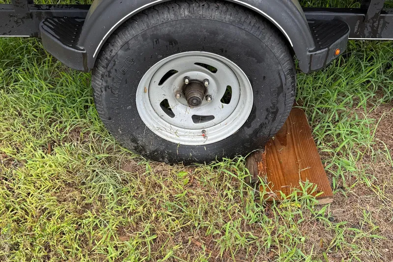 Slide: The Image of Trailer wheel of 2017 Sun Tracker Bass Buggy 18 DLX on grass with wooden block. - 20