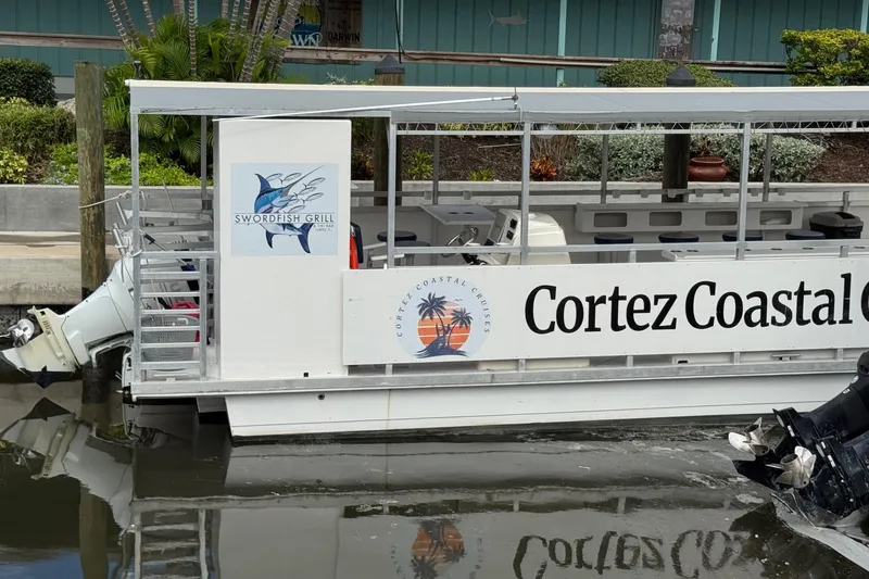 Slide: The Image of 2022 Guthrie Boatworks A&M Custom Pontoon docked, featuring Swordfish Grill and Cortez Coastal Cruises signage. - 12