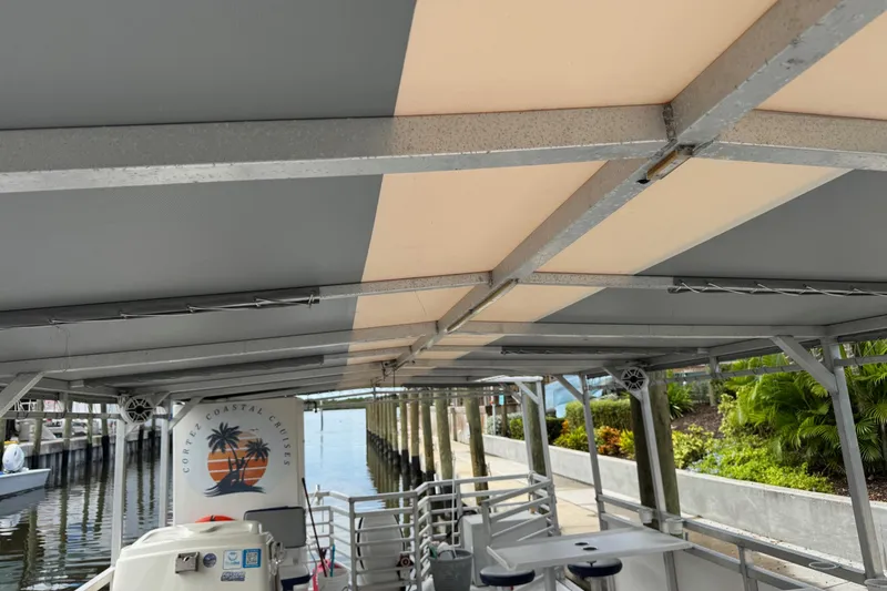 Slide: The Image of 2022 Guthrie Boatworks A&M Custom Pontoon with canopy, docked near lush greenery. - 16