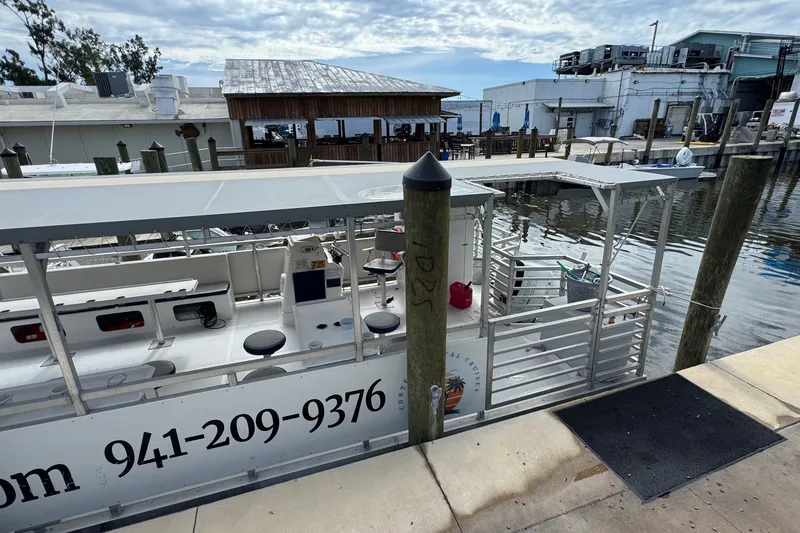 Slide: The Image of 2022 Guthrie Boatworks A&M Custom Pontoon docked at a marina with surrounding buildings. - 6