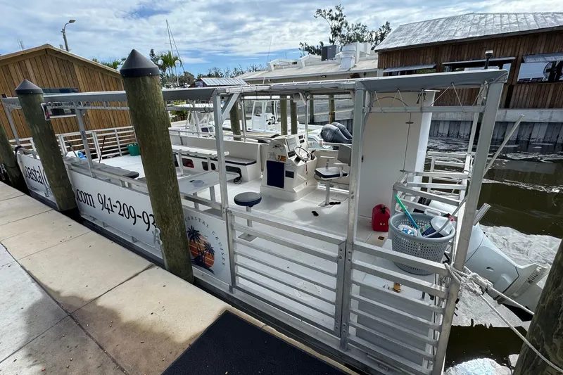 Slide: The Image of 2022 Guthrie Boatworks A&M Custom Pontoon docked at marina, featuring open deck and seating. - 7