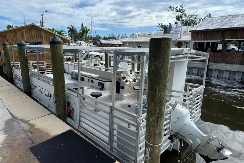 Slide: The Image of 2022 Guthrie Boatworks A&M Custom Pontoon docked at marina, surrounded by wooden structures. - 8