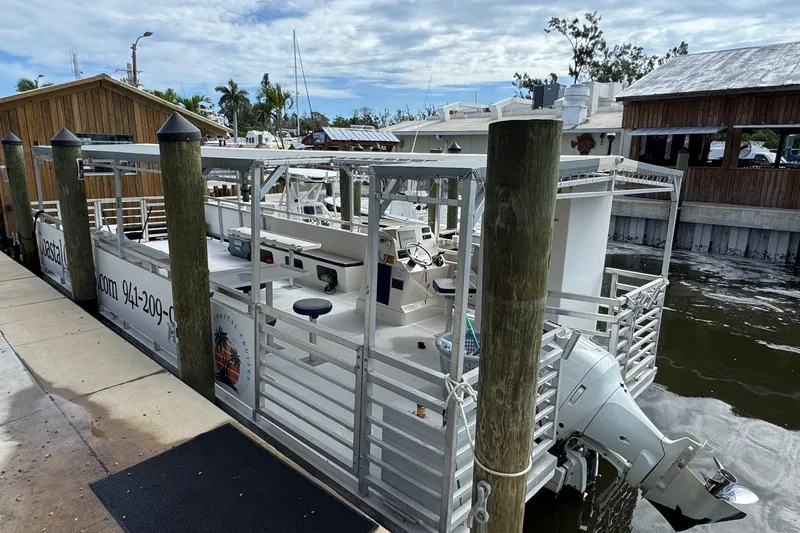 Slide: The Image of 2022 Guthrie Boatworks A&M Custom Pontoon docked at a marina, featuring a sleek design. - 9